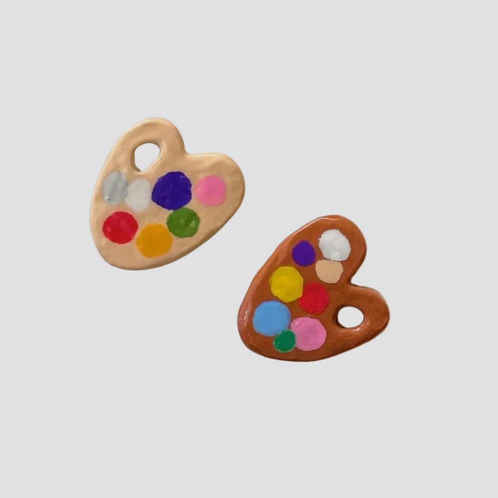 Two heart-shaped ceramic potters' palettes with colorful dots on a white background