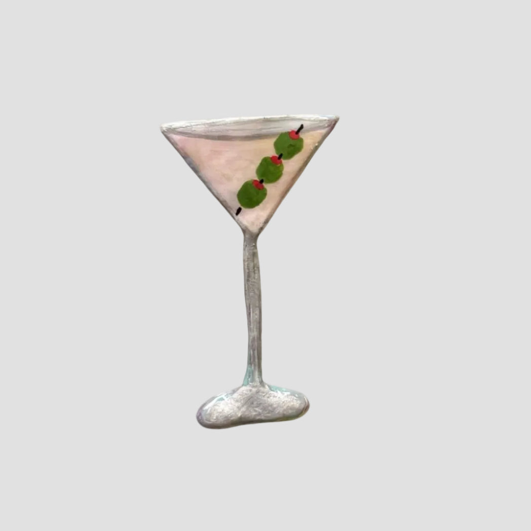 Martini glass with a cocktail and olives on a white background