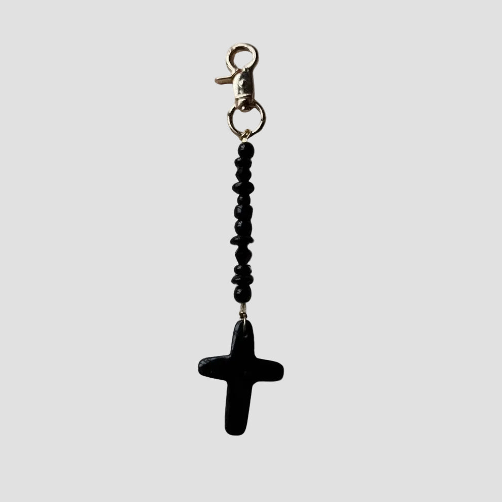 Black cross charm on a white background