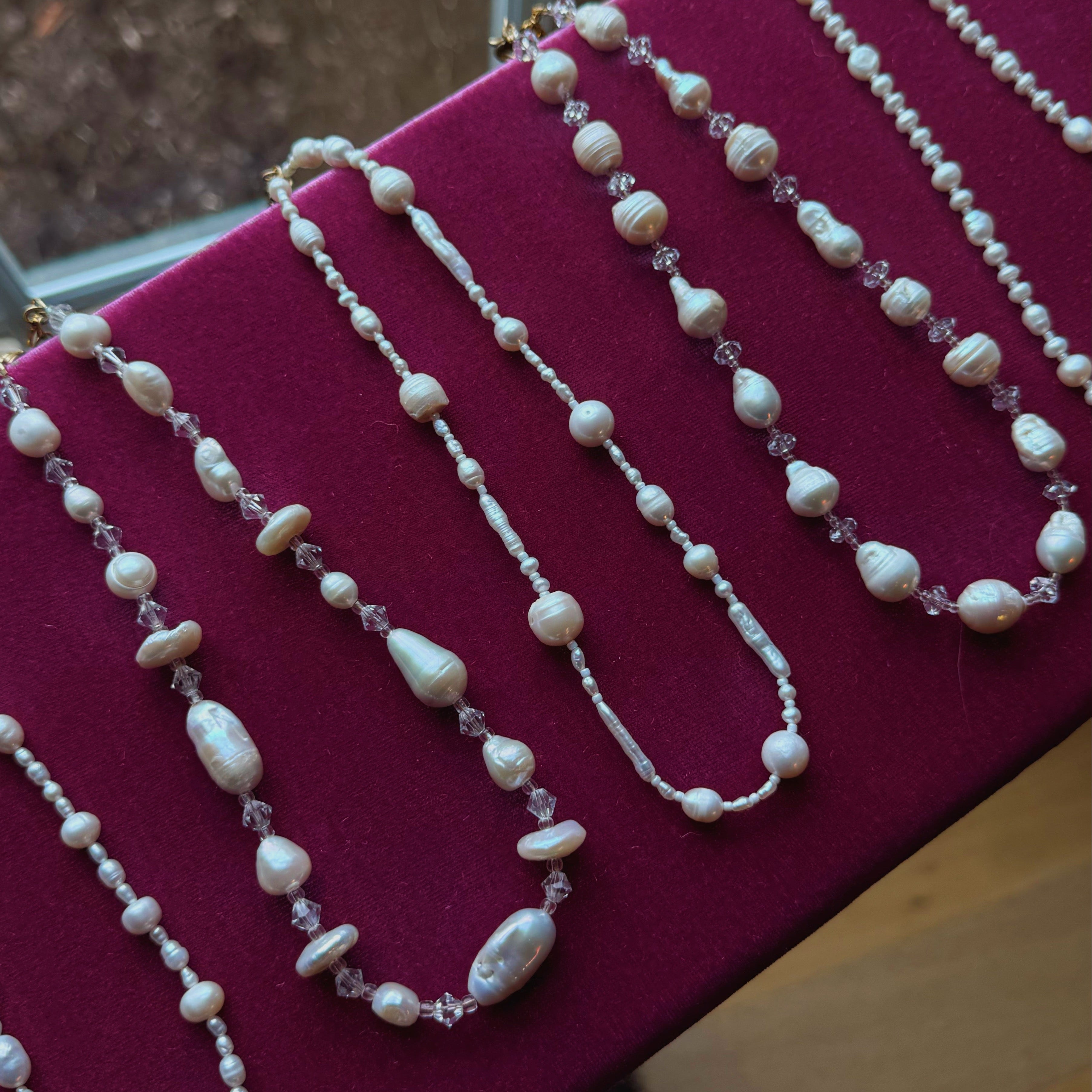 Pearl necklace on a pink cushion with a blurred background