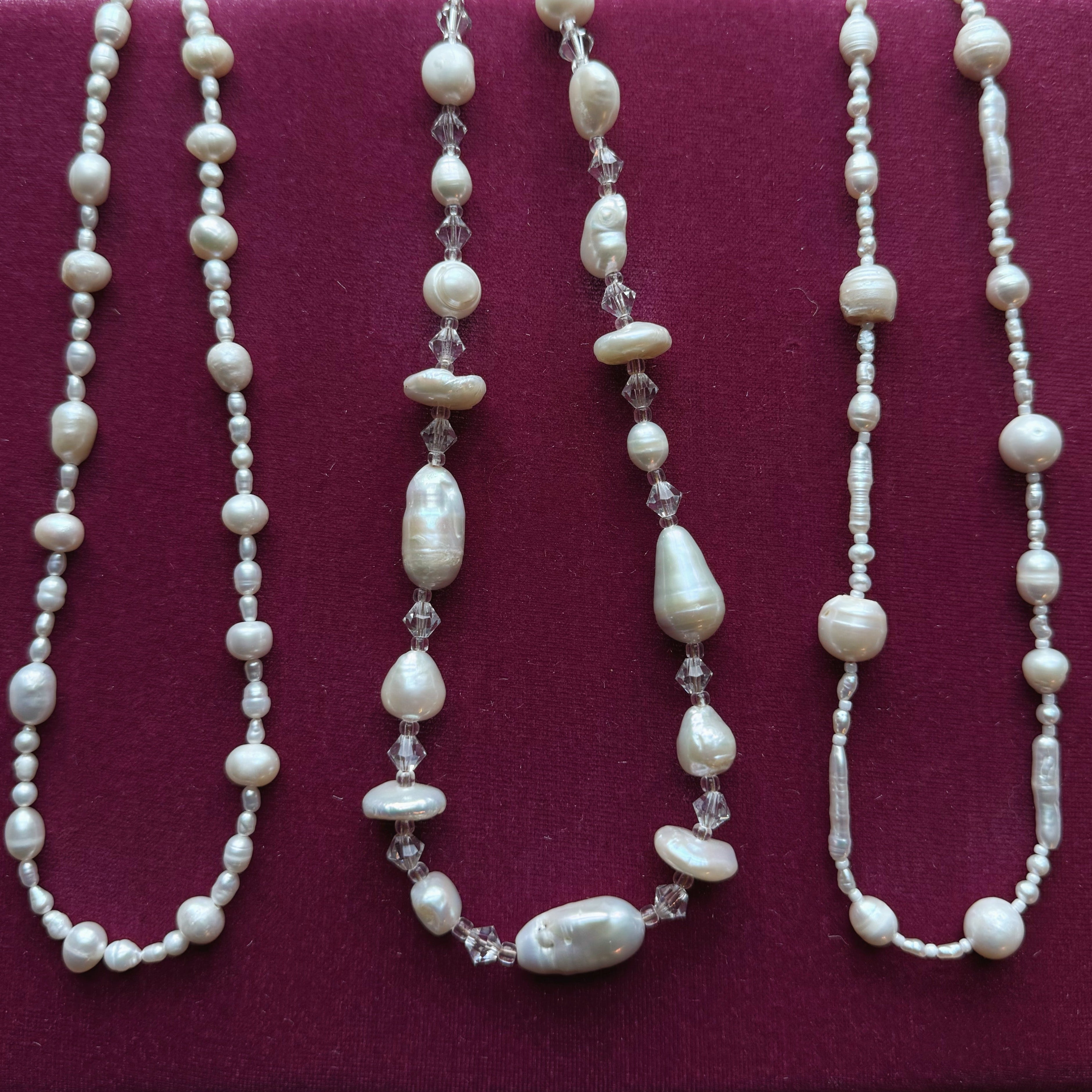 Three pearl necklaces with crystal accents on a pink background