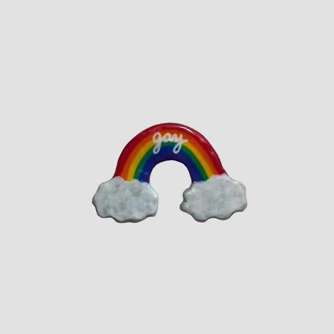 Small rainbow-shaped object with 'joy' on a beige surface