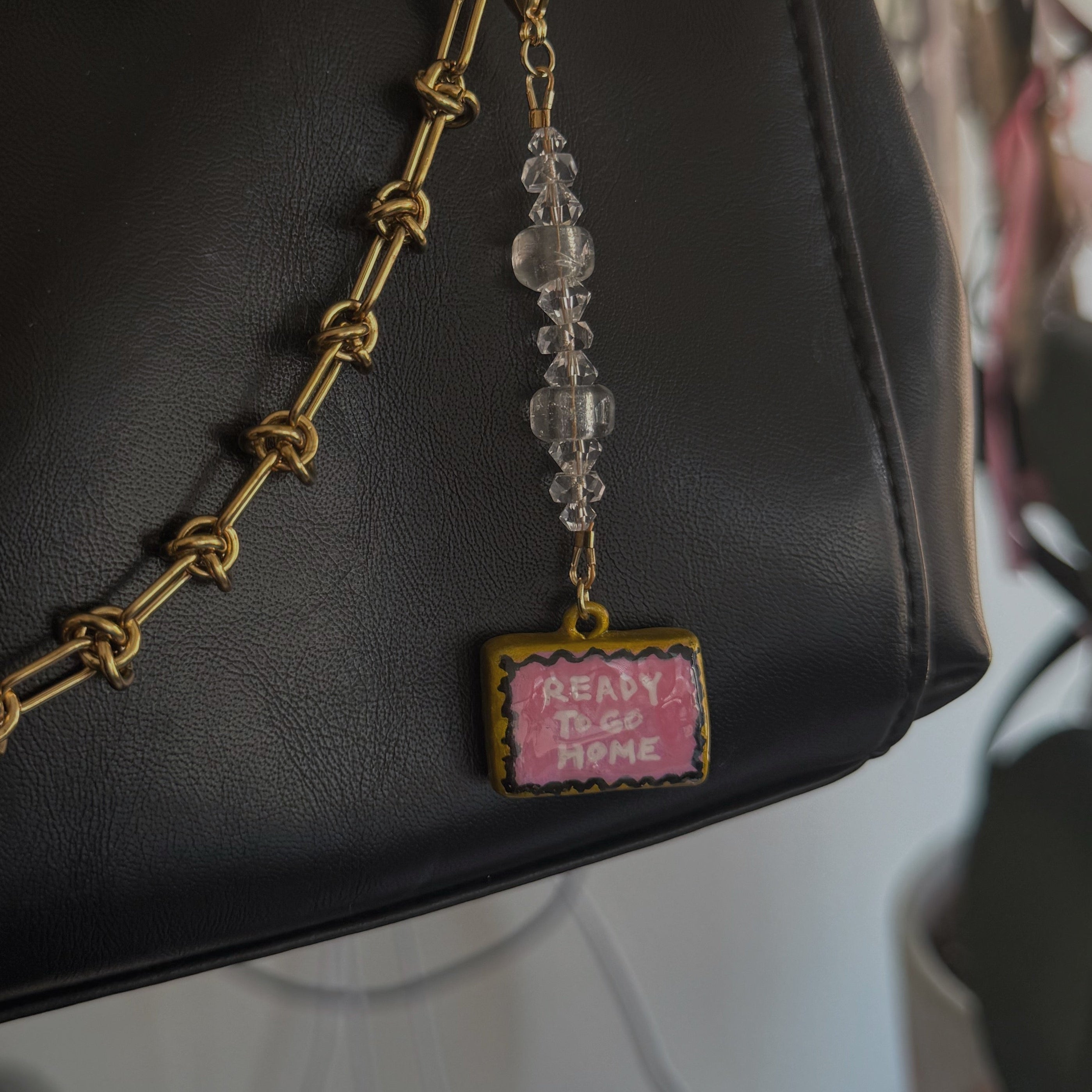 Black handbag with a gold chain and pink tag on a blurred background