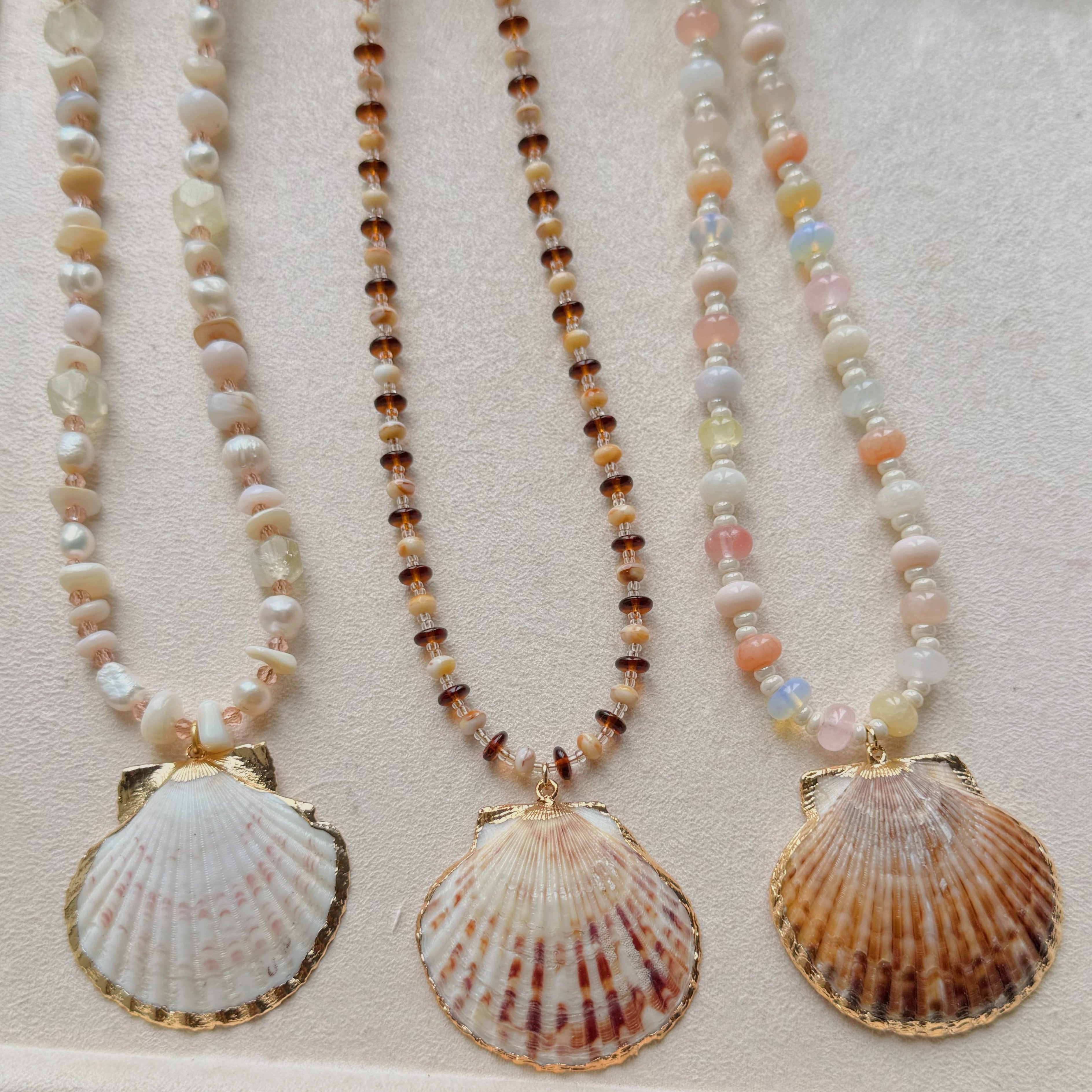 Three shell pendant necklaces on a light background