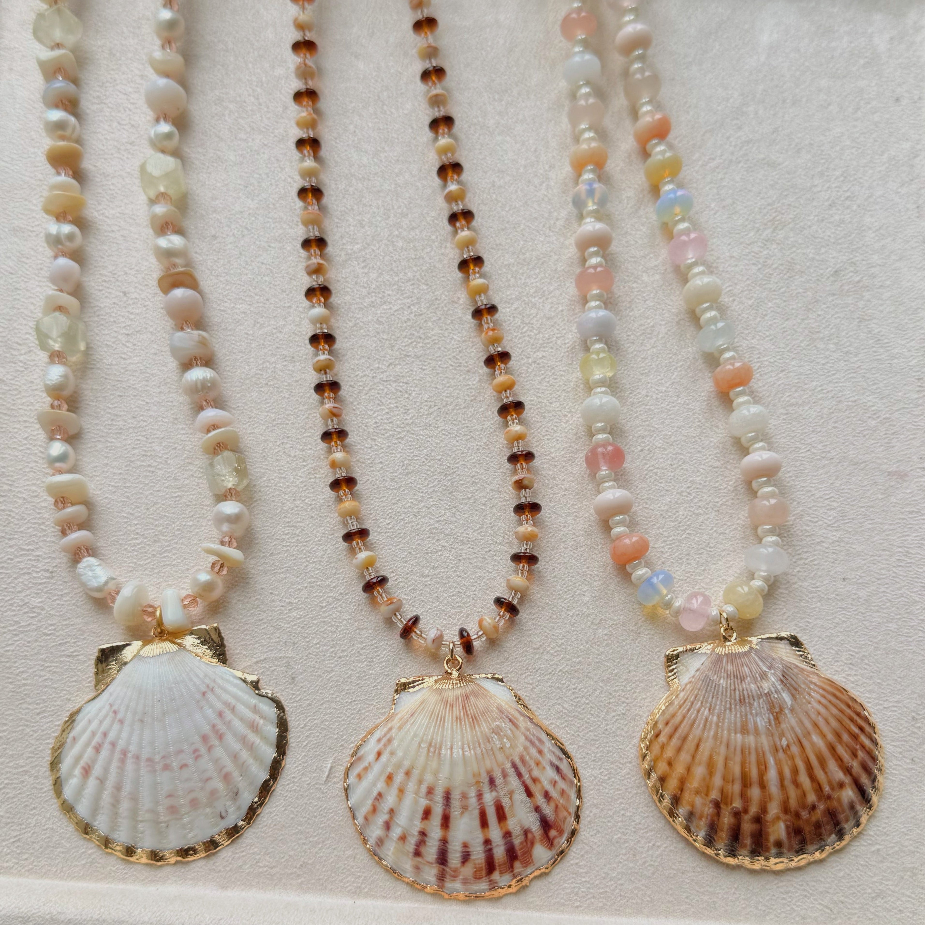 Three shell pendant necklaces on a light background