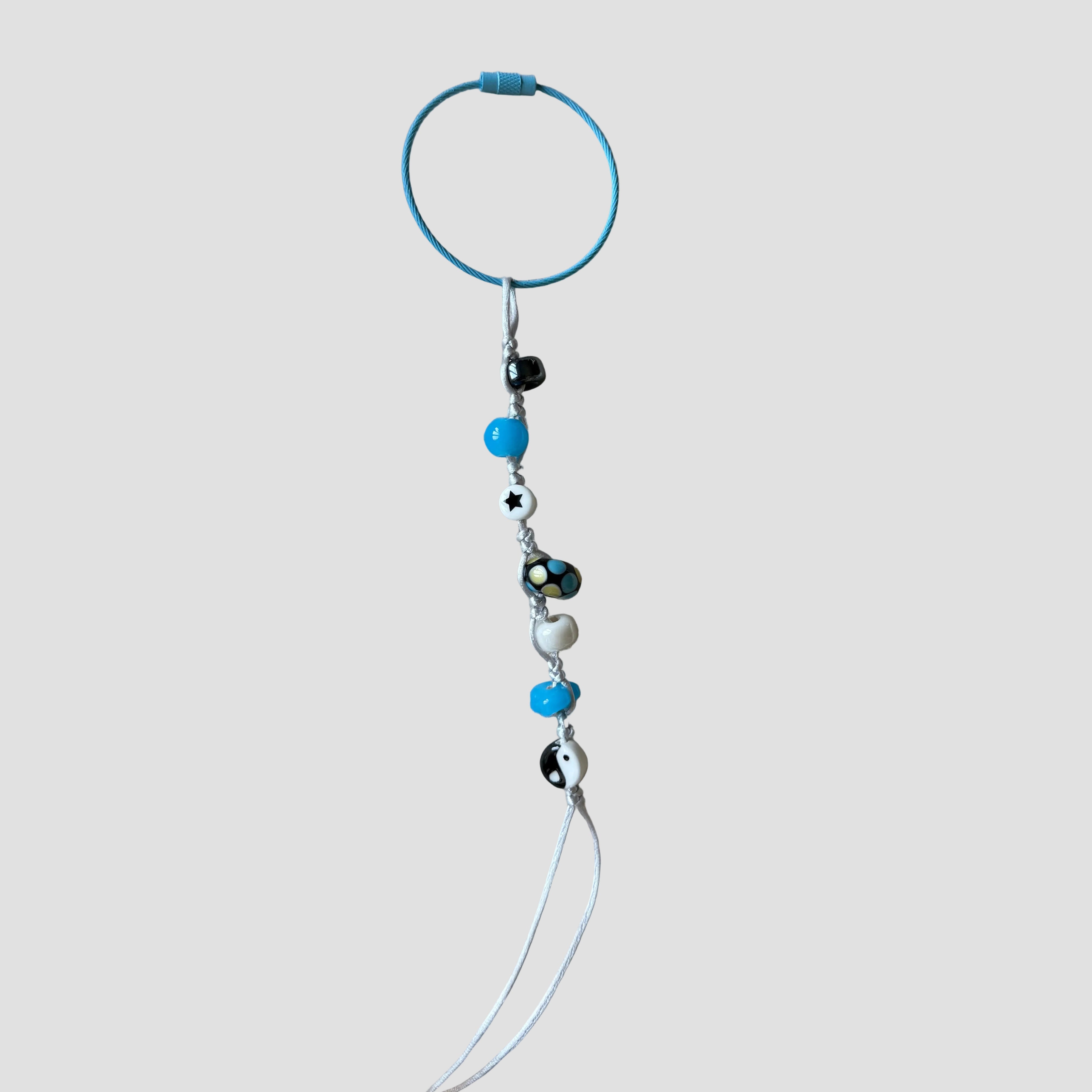 Beaded keychain with blue and black beads on a beige tray